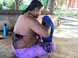 A schoolteacher in the midst of receiving a full pe'a