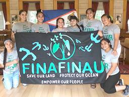 Finafinau members with sign saying save our land, protect our ocean, empower our people