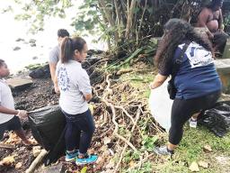 Students remove debris from along the shoreline of the Pala Lagoon