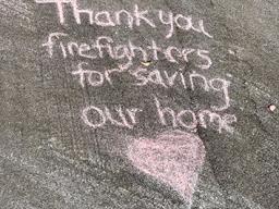 thank you message chalked on the driveway of a home that was spared.