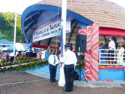 Police officers prepare to raise flags while VIPs watch from the background.