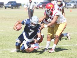 Samoana Sharks quarterback Viliamu Tanielu is brought down by three Tafuna Warrior defenders
