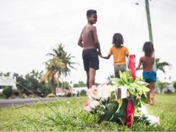 Village children walk past a cross planted at Faleula 