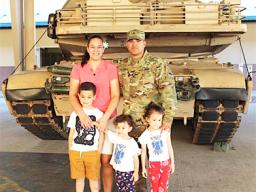 DeAngelo Herrera and family posing in front of a tank