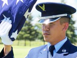 Senior Airman Darias Faaita preparing to present an American Flag to its recipient.