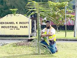 The  Sen. Daniel K. Inouye Industrial Park sign with man 