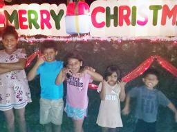 The Uelese siblings in front of a Merry Christmas display in Aoloau