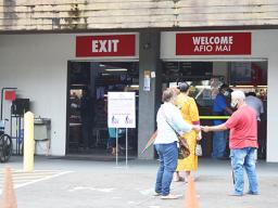 People lining up waiting to get into a store with social distancing inforced