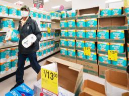 A masked customer grabs two packages of toilet paper at Longs Drugs in Moiliili.