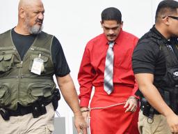 Manu Lefatia restrained and escorted by two police officers