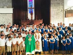 Most Reverend Bishop Peter Hugh Brown (front, center) who is pictured with St. Theresa Elementary School chaplain, Reverend Father Kolio Etuale; St. Theresa Elementary School principal Victor Langkilde (far left), staff members and students.