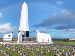 Small American Flags in front of Veterans Memorial Monument with rainbow overhead