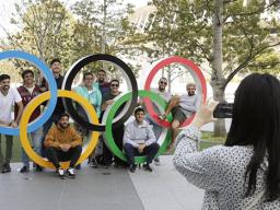 A group of students from Uruguay pose for a souvenir picture on the Olympic Rings set outside the Olympic Stadium in Tokyo