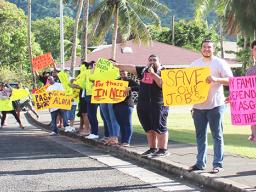A group of about 15 peaceful protesters on the sidewalk in front of Utulei Beach