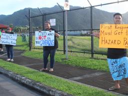 Three protesters with signs protesting governer's checks to fono