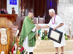 shows Tualauta Faipule Larry S. Sanitoa (right) shaking hands with Bishop Kolio Etuale Tumanuvao,