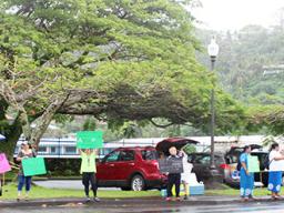 A group of residents - some with umbrellas - participating  in the “Wave for repatriation flights - Not open borders”