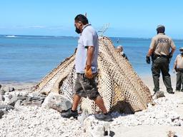 Saute Sapolu looking out from behind his fale as Honolulu cops dismantle it.