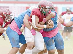 Tafuna High School’s powerback is gang-tackled by three Samoana defenders 