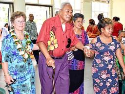 Evelyn Lili’o Satele (left) helps escort an elderly member of the community
