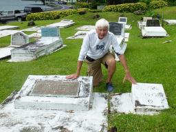 Tom Blake touches the two gravestones in Pago Pago, of his friend Mark Flannery’s parents