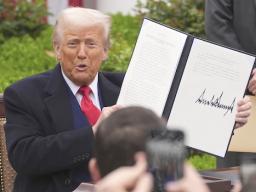 President Donald Trump holds a signed executive order