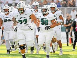 John Tuitupou with other UH Rainbow Warriors taking the field