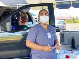 Healthcare worker with mask standing beside a car