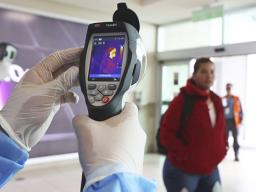 A Health Ministry staffer monitors the body temperature of travelers n Quito, Ecuador