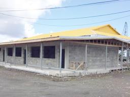 Gym and adjoining building in progress with two workmen on roof