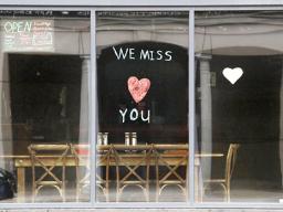 Sign in the window of empty cafe saying, "We miss you"