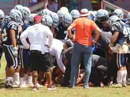 Samoana Sharks varsity squad huddling around one of their injured players