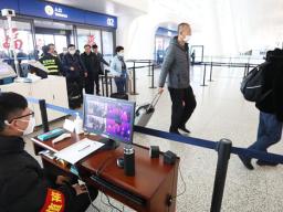 Staff members take passengers' body temperature at Tianhe International Airport in Wuhan