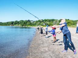 Janet Coit casts her line into the water with others in background