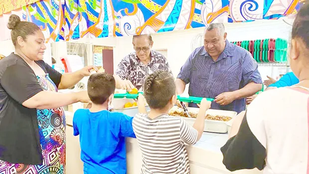 Gov. Lemanu Peleti Palepoi Sialega Mauga serving a line of children lunch