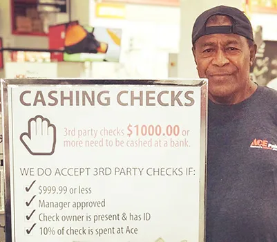 ACE employee beside their check chasing policy sign
