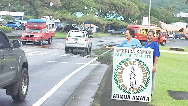 Amata waving behind a thank you sign.  A passerby stops to help out.
