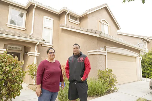 Makerita Iosefo-Va'a and her husband Shaun Va'a pose in front of a relative's home