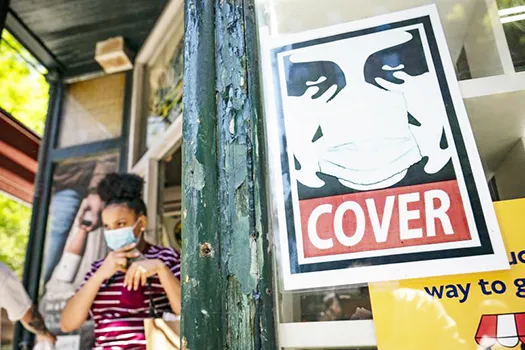 Young woman with mask near masking sign.