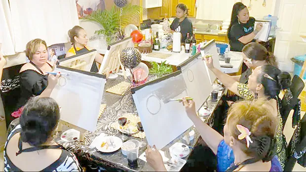 Women painting sitting around a large table