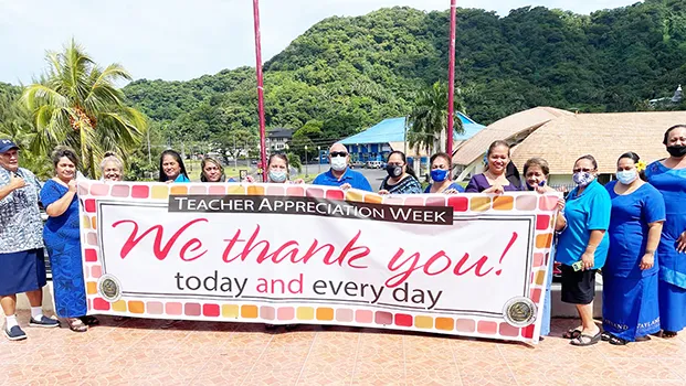 DOE admin holding up Teacher Appreciation Week banner