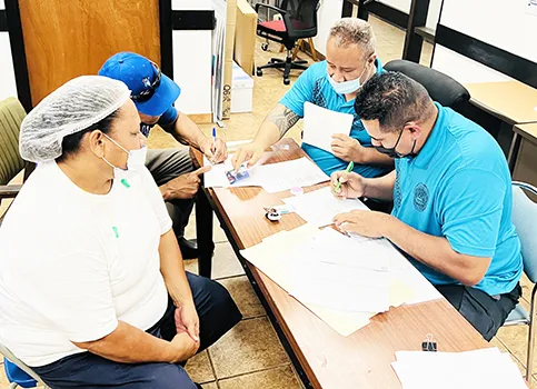 Two employees with Joseph Felise (right, at back), Solefai Tapuala (right, front) at the StarKist HR Office