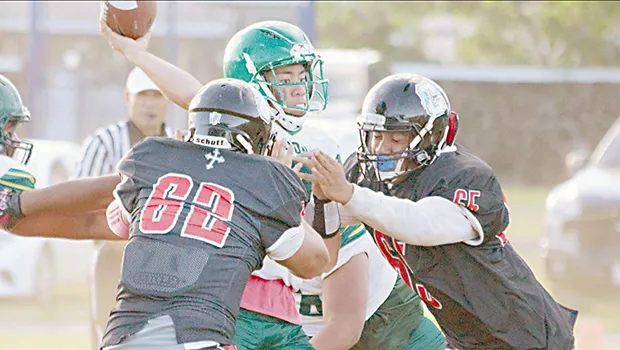 Leone Lions quarterback, Elisara focused and locked-in to make a pass just before getting tackled by two Marist Crusader defenders 