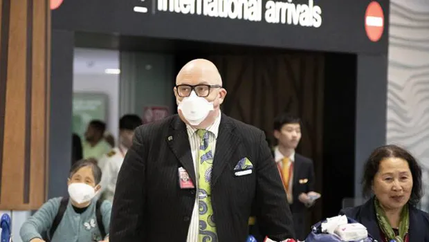 Travellers wearing face masks exit the arrivals hall at Auckland International Airport