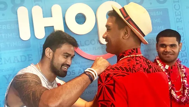 Samoan NFL player Shalom Luani autographing a shirt for one of the players from the U18 Amerika Samoa National Baseball Team