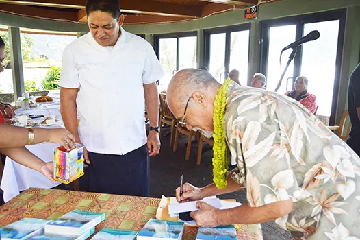 Fuimaono Fini Aitaoto signing the cover of his book