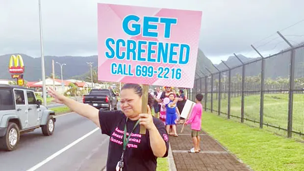 Woman with "get tested" sign for Breast Cancer Awarenss Month