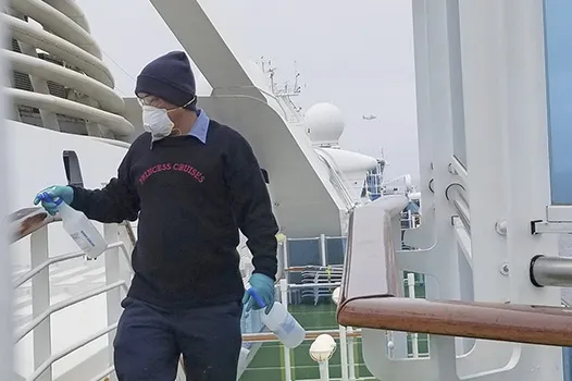 A cruise ship worker cleans a railing on the Grand Princess 