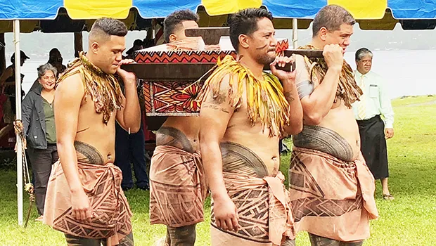4 young men with traditional tattoos carry the 2020 American Samoa quarter in a tapa decorated box