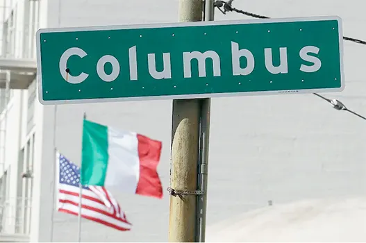 Street sign that says Columbus with flags in background